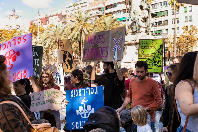 Manifestación ciudadana con pancartas sobre la crisis climática y la contaminación urbana, ilustrando la importancia de la comunicación estratégica para generar consenso. Citizens demonstrating with placards about the climate crisis and urban pollution, illustrating the importance of an effective urban communication strategy to build consensus.