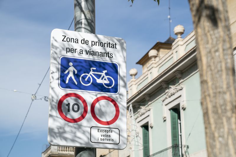 Señalización vial de prioridad peatonal y de ciclistas con límite de velocidad a 10 km/h en una zona con estrategia de comunicación para la pacificación del espacio público. Traffic sign for pedestrian and cyclist priority with a 10 km/h speed limit, illustrating urban space pacification and urban communication strategy. 